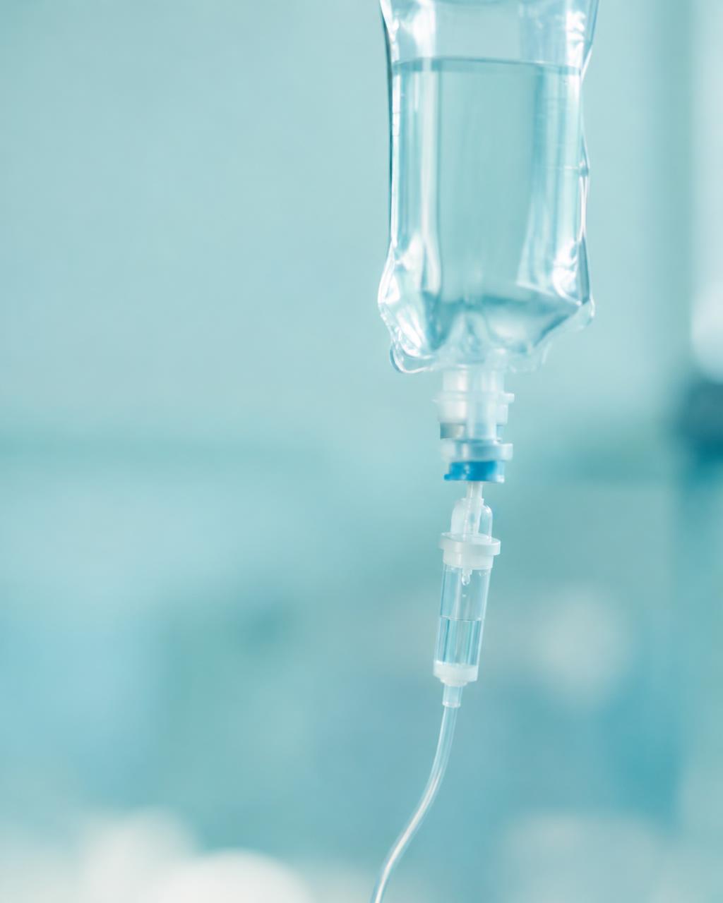 Close-up of an IV hydration bag against a soft aqua background